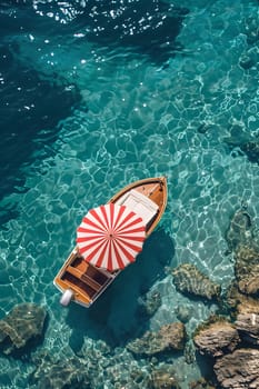 A small boat with a red and white striped umbrella floats on a clear blue sea with rocky shores in the background