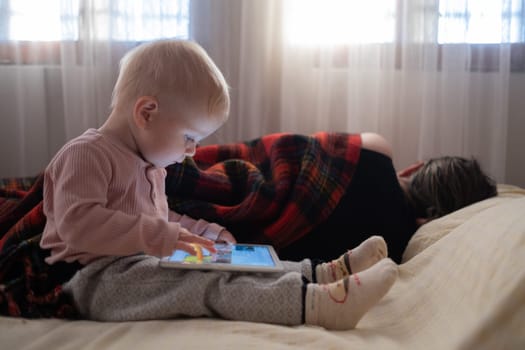 caucasian child girl playing with a digital tablet at home.