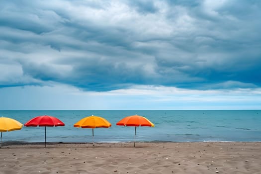 Four colorful umbrellas stand on a sandy beach, creating a vibrant contrast against the dramatic blue sky with puffy clouds. The water, with the horizon in the background, is calm and serene, evoking a sense of tranquility and relaxation.