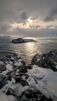 A snowy island with sun rays shining through the clouds.