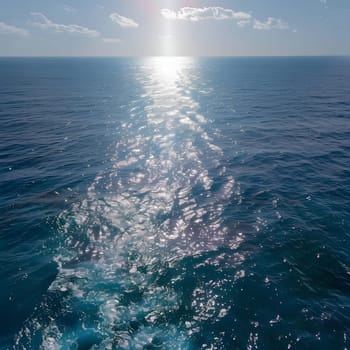 A long wake left behind a boat, with the sun sparkling on the surface of the ocean.