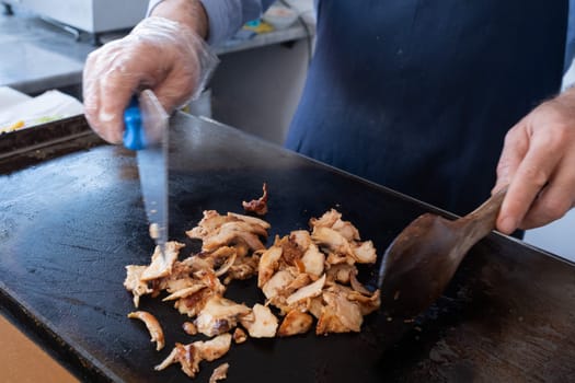 Close-up of a chef cutting meat with a knife for a traditional street food doner kebab or shawarma