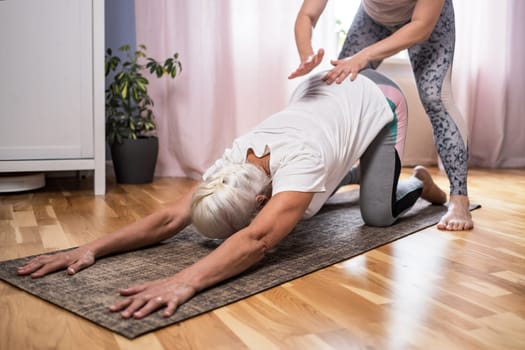 Elderly woman doing pilates on mat in female group at home alone