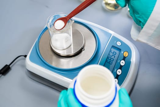A woman utilizes laboratory balances to measure powder samples.
