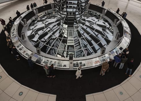 Berlin, Germany - Dec 20, 2023 - Several tourists visitor inside the futuristic glass dome of Reichstag building. Contemporary architecture of the Cupola of the Reichstag dome, a major tourist attraction of the berlin city, Copy space, Selective focus.