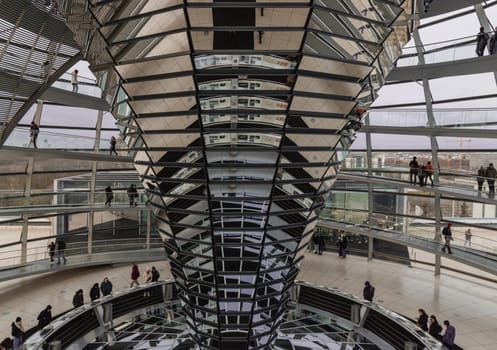 Berlin, Germany - Dec 20, 2023 - Several tourists visitor inside the futuristic glass dome of Reichstag building. Contemporary architecture of the Cupola of the Reichstag dome, a major tourist attraction of the berlin city, Copy space, Selective focus.