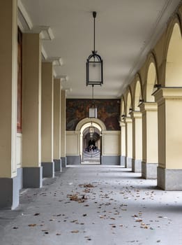 Munich, Germany - Dec 21, 2023 - Perspective view of Long corridor with Antique lantern hanging from ceiling and Beautiful columns inside Hofgartenarkaden (Munchen). Design elements of European architecture structure, Space for text, Selective focus.