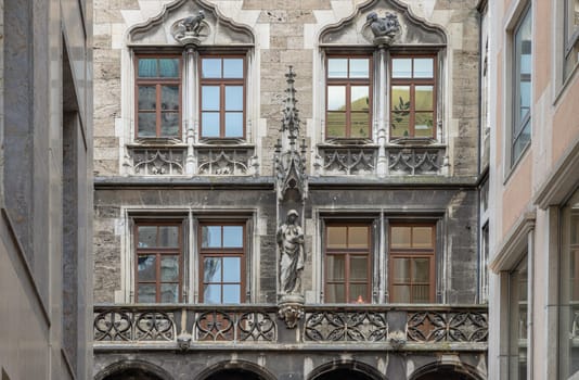 Munich, Germany - Dec 21, 2023 - Sandstone Building with many Windows is Decorated with Statues with Gothic style. Exterior architecture design of famous New Town Hall (Neue Rathaus) on Marienplatz square in Munich, Space for text, Selective focus.