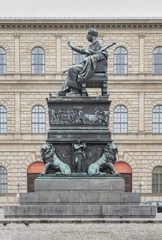 Munich, Germany - Dec 21, 2023 - Side view of Monument Bronze Statue of King Maximilian I Joseph of Bavaria with The Munich Residence Museum Building at the Max Joseph Square in central Munich. Space for text, Selective focus.