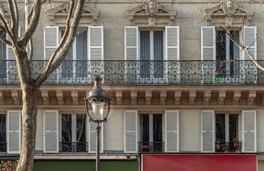 France, Paris - Jan 05, 2024 - Facade of elegant apartment buildings in the cities of Paris are patterned with french windows and wrought iron black railings. Exterior architecture of Traditional French house with typical balconies and windows in Paris, Copy space, Selective focus.