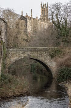 Edinburgh, Scotland - Jan 16, 2024 - View from the Dean Village towards Holy Trinity Church, now the Rhema Christian Centre Church with Dean Bridge and The Water of Leith flowing through Dean Village in the foreground. Space for text, Selective focus.