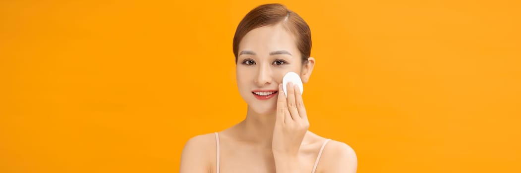 Healthy fresh woman removing makeup from her face with cotton pad on  banner background