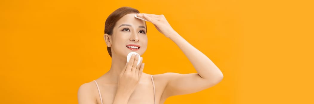 Asian young woman using cosmetic pad or cotton pad remove makeup cares for face skin, banner.