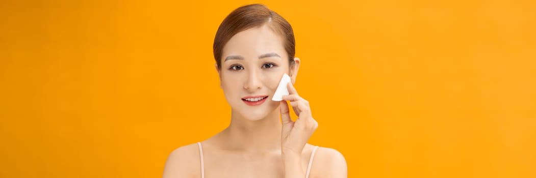 Healthy fresh woman removing makeup from her face with cotton pad on  banner background