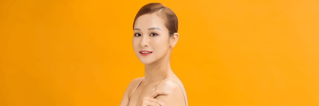 Banner of beauty smiling asian woman applying a lotion to her arm skin during her dressing up