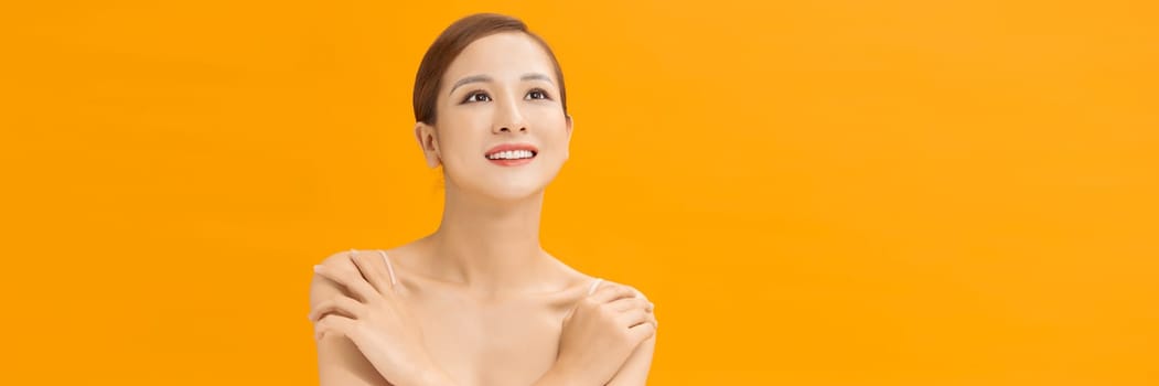 Youthful smiling Asian woman isolated on yellow banner background for beauty and skin care concepts