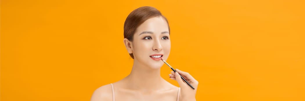 young beautiful asian woman applied lipstick on banner background