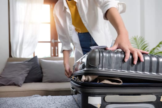 Woman tries to close a suitcase full of belongings in preparation for a holiday trip..