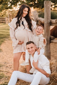 Happy family near horses at a farmer's ranch at sunset.