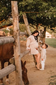 A pregnant woman with her son walks in the countryside in the summer.