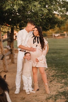 Happy family near horses at a farmer's ranch at sunset.