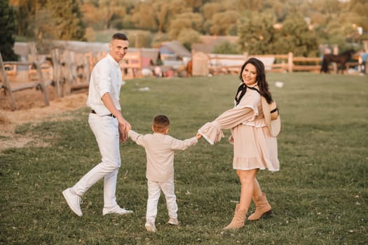 A stylish family in the countryside at sunset. A pregnant woman with her husband and son in nature.