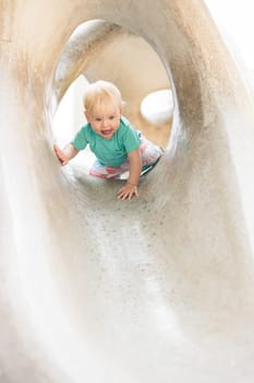 Child playing on outdoor playground. Toddler plays on school or kindergarten yard. Active kid on stone sculpured slide. Healthy summer activity for children. Little boy climbing outdoors