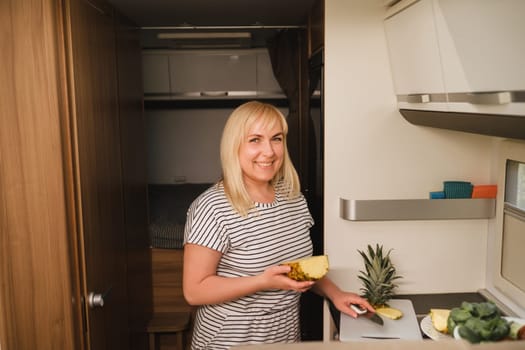 a woman cooking food in the kitchen inside a motorhome, the interior of a motorhome.