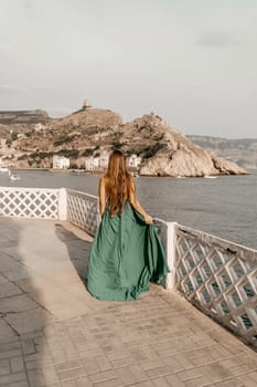 Woman sea green dress. Side view a happy woman with long hair in a long mint dress posing on a beach with calm sea bokeh lights on sunny day. Girl on the nature on blue sky background