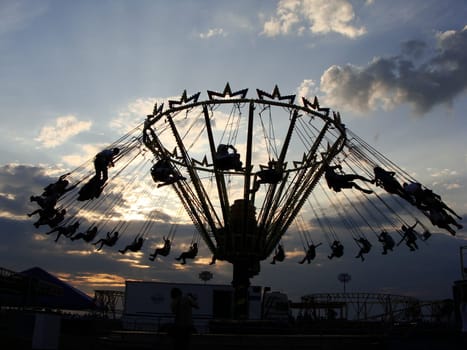 People ride on a carousel. Silhouettes of people riding on a carousel at sunset. High quality photo