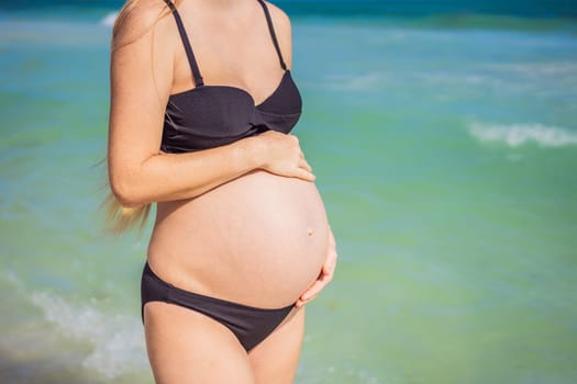 Radiant pregnant woman in a swimsuit, amid the stunning backdrop of a turquoise sea. Serene beauty of maternity by the shore.