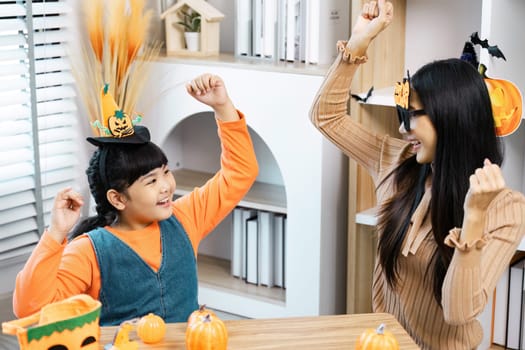 A joyful mother and daughter enjoying Halloween festivities with fun costumes and decorations in a cozy home setting.