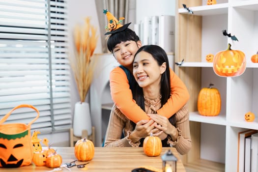 A joyful mother and child enjoying Halloween festivities with pumpkins and decorations in a cozy home environment.