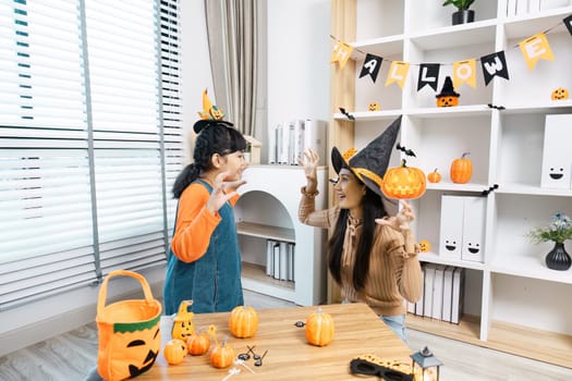 A mother and daughter enjoying Halloween festivities at home, surrounded by decorations and wearing costumes.