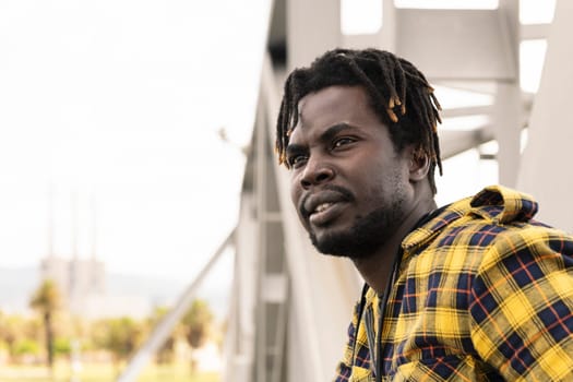 portrait of a young african man with a metal structure in the background, modern lifestyle concept, copy space for text