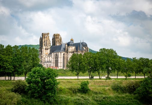 Distant view of the Cathedral of Toul with lot of green trees and plants in the park from the bridge over the Moselle