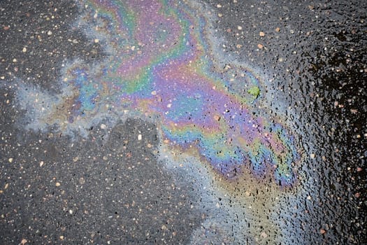 Close-up of a Glimmering Oil or Gas Spill on Rain-soaked Tarmac, Viewed from Above