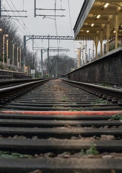 London, UK - Dec 25, 2023 - Railway iron rails from the low perspective. Railroad tracks with limited depth of focus, The Railway system with Metal frames of Train platform, Railroad track rails, Train tracks, Railway station, Space for text, Selective focus.