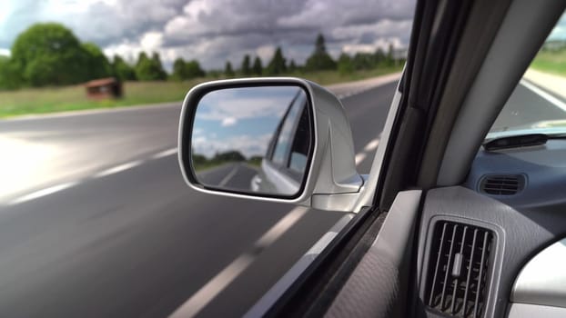 A car drives along a picturesque highway under cloudy skies.