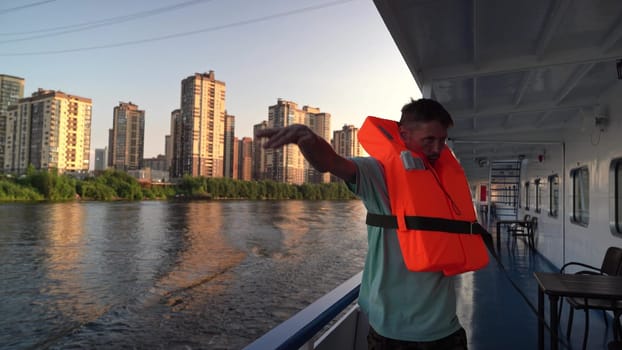 Russia, St. Petersburg , July 26 , 2024 - man in a bright life jacket greets from a boat by the water.