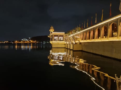 Jagmandir island palace with beautiful lights reflected in water with arches, elephant statues and arched windows in Udaipur in India