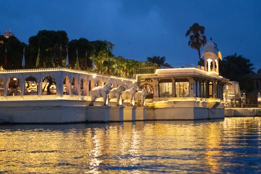 Jagmandir island palace with beautiful lights reflected in water with arches, elephant statues and arched windows in Udaipur in India