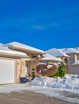 Entrance of luxury house with driveway and front yard in snow. Winter season in canadian suburb