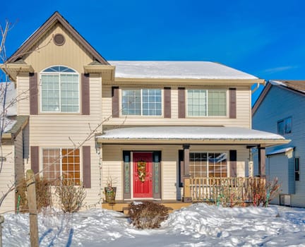 Luxury residential house with front yard in snow. Femily house decorated for christmas celebration on winter sunny day
