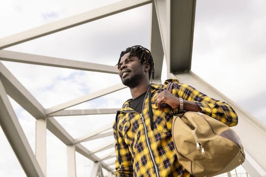 young black man with a large travel bag walking on a metal structure, lifestyle and travel concept