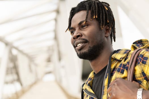 portrait of a young african man passing through a modern metal structure to access to the airport, lifestyle and travel concept