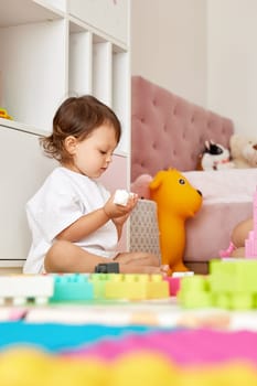 cute baby girl playing with colorful toys bricks at home