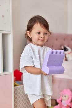 cute baby girl playing with colorful toys bricks at home