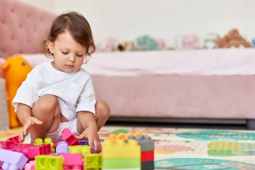 cute baby girl playing with colorful toys bricks at home, copy space