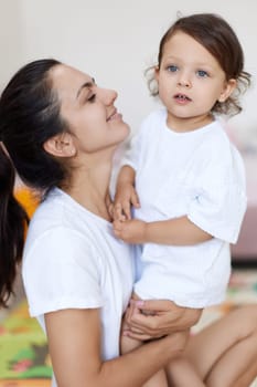 happy mother with cute baby girl in white t-shirt having fun together